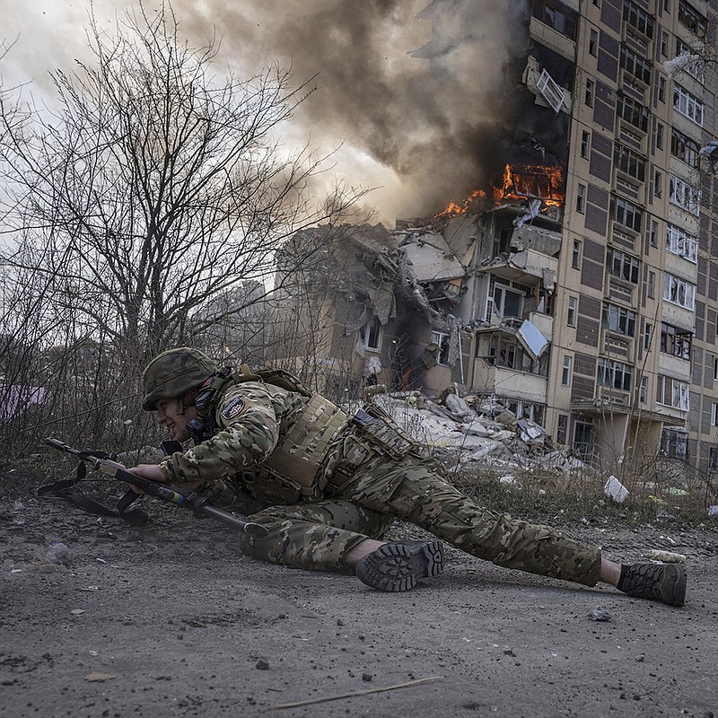 A Ukrainian police officer takes cover in front of a burning building that was hit Friday in a Russian airstrike in Avdiivka, Ukraine. More photos at arkansasonline.com/ukrainemonth13/.
(AP/Evgeniy Maloletka)