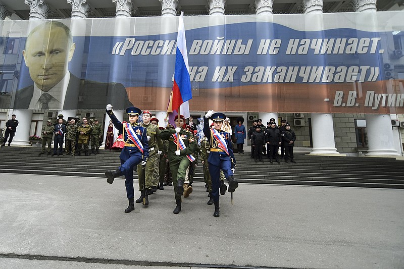 Youth take part in an action to mark the ninth anniversary of Crimea annexation from Ukraine with a banner reading: "Russia doesn't start wars, it ends them" accompanied with an image of Russian President Vladimir Putin, in Yalta, Crimea, Friday, March 17, 2023. (AP Photo)