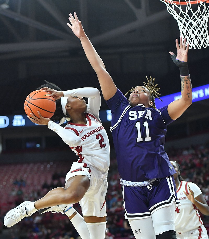 Arkansas guard Samara Spencer (2) reaches to score Monday, March 20, 2023, as Stephen F. Austin forward Avery Brittingham (11) defends during the first half of play in Bud Walton Arena in Fayetteville. Visit nwaonline.com/photo for today's photo gallery. .(NWA Democrat-Gazette/Andy Shupe)