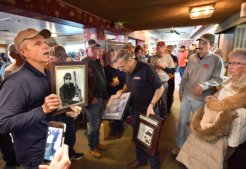 Shawn Looper (left) of Looper Auction and Realty holds up a photograph of musician Roy Orbison during an auction at the former AQ Chicken House restaurant in Springdale on Wednesday. The business is closed after operating since 1947. More photos at arkansasonline.com/323aqbidders/.
(NWA Democrat-Gazette/Andy Shupe)