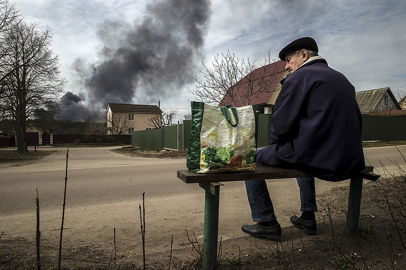 Smoke from a Russian attack rises in the distance Thursday as a man waits for a bus outside the city of Zhytomyr about 90 miles west of Kyiv.
(The New York Times/Tyler Hicks)