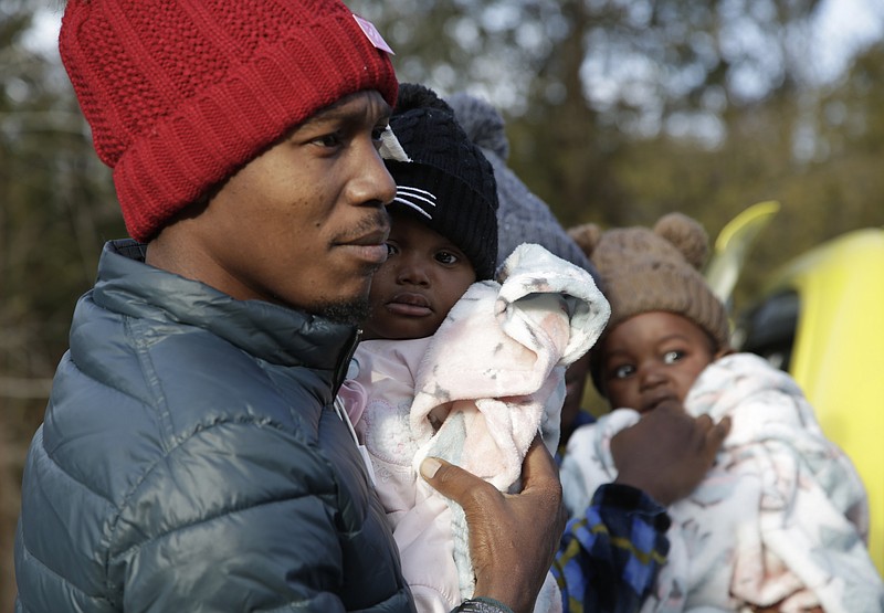 Haitian migrant Gerson Solay, 28, carries his daughter, Bianca, as he and his family cross into Canada at the non-official Roxham Road border crossing north of Champlain, N.Y., on Friday, March 24, 2023. A new US-Canadian migration agreement closes a loophole that has allowed migrants who enter Canada away from official border posts to stay in the country while awaiting an asylum decision. (AP Photo/Hasan Jamali)