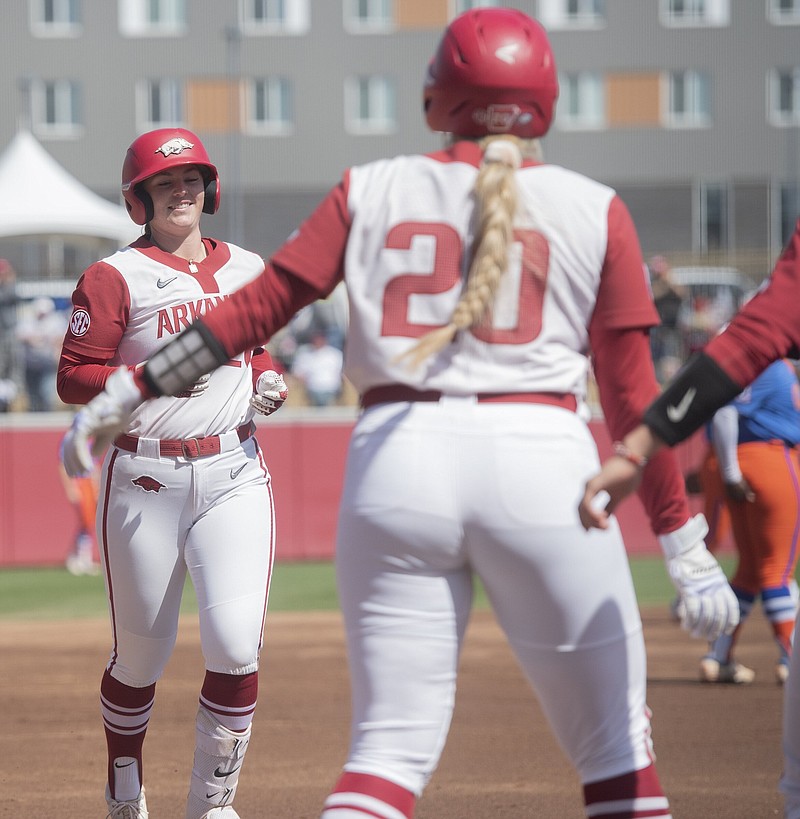 Arkansasâ€™ Rylin Hedgecock ((CQ)) is greeted at home plate by Hannah Gammill (20) after scoring in the first inning against Florida Sunday March 26, 2023 at Bogel Park in Fayetteville. The Razorbacks won 14-1 in 5 innings. Visit nwaonline.com/photo for today's photo gallery.   (NWA Democrat-Gazette/J.T. Wampler).