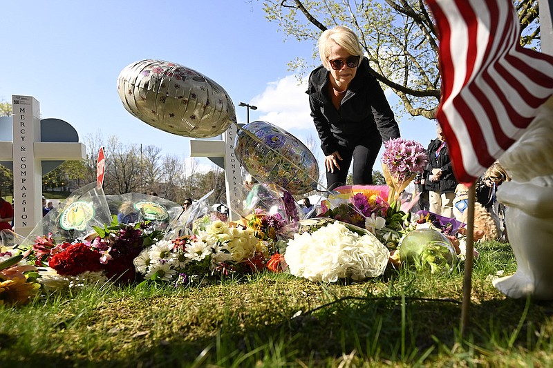 A woman leaves flowers at a growing memorial, Tuesday, March 28, 2023, in Nashville, at an entry to Covenant School for the victims of Monday' shooting. (AP Photo/John Amis)