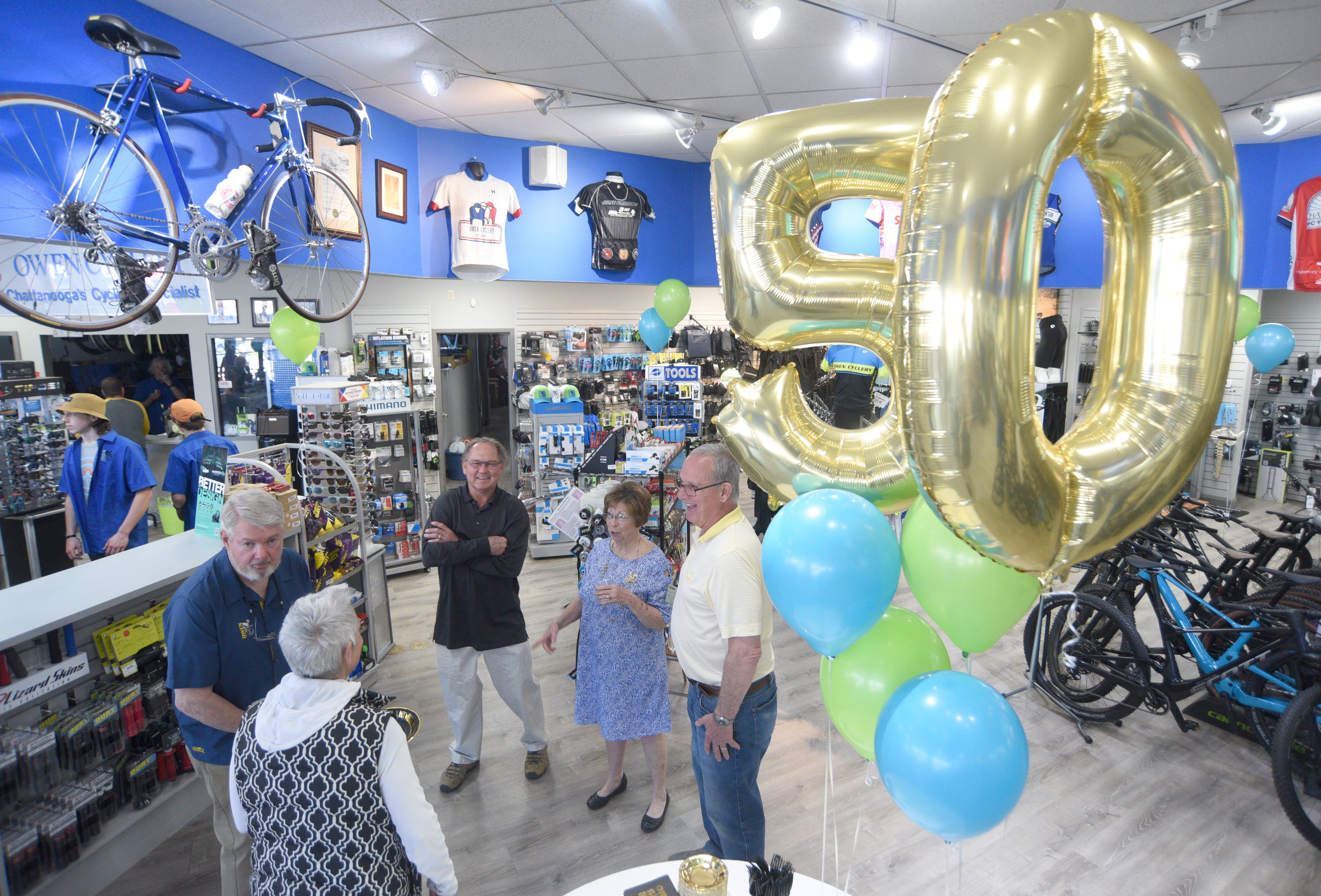 Staff photo by Matt Hamilton / Tom Owen, left, and his wife Marbeth Owen, middle right, talk to other guests during the 50 year celebration for Owen Cyclery in Hixson. on Thursday, March 30, 2023.