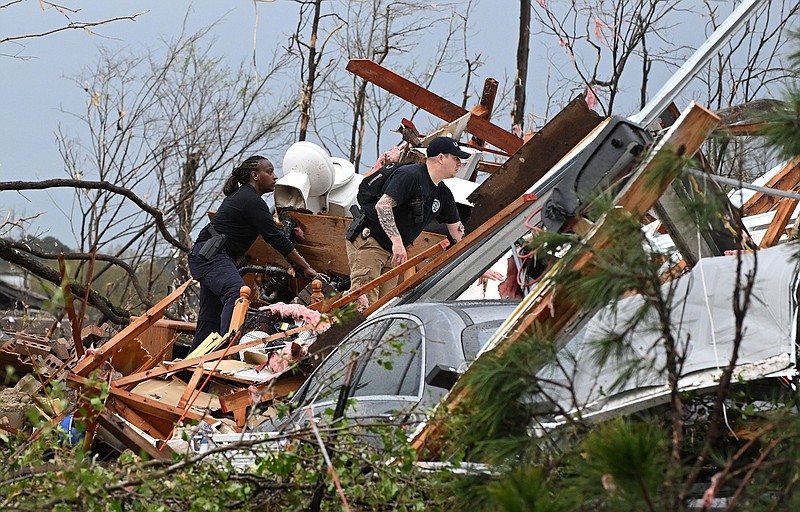 Responders check through storm damage Friday in the Walnut Valley area of west Little Rock after a tornado ripped through, tossing vehicles and trees and damaging buildings. More photos at arkansasonline.com/41storm/.
(Arkansas Democrat-Gazette/Staci Vandagriff)