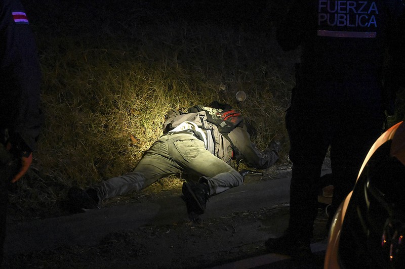 FILE - The body of a man is illuminated by police flashlights as investigators work a crime scene where an alleged thief and a female passenger died in a shootout during a robbery on a bus in San Jose, Costa Rica, Feb. 6, 2023. According to the authorities, the Central American nation has reached its highest murder rate since the Organization of Judicial Investigation office has kept records. (AP Photo/Carlos Gonzalez, File)