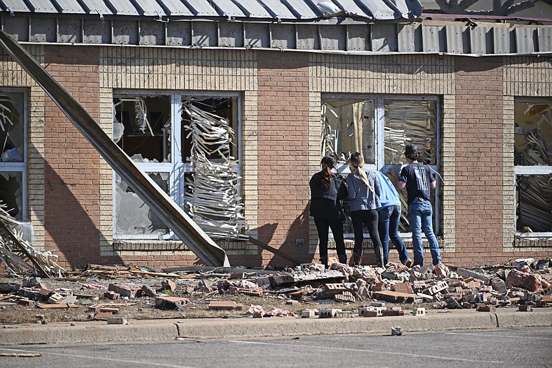 People look through the windows of the storm-damaged Wynne High School on Saturday as cleanup from Friday’s deadly tornado began. More photos at arkansasonline.com/42wynne/. (Arkansas Democrat-Gazette/Staci Vandagriff)