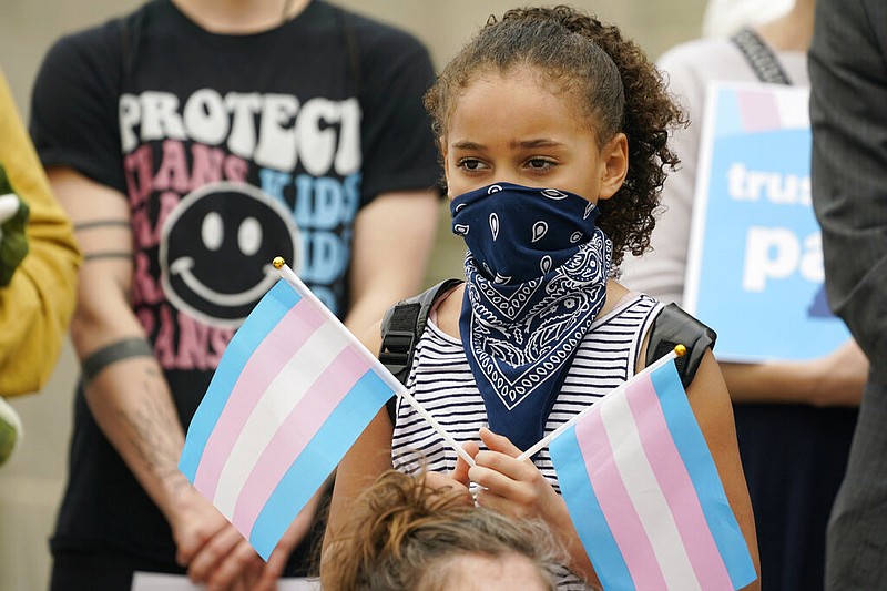 A young child holds a pair of trans pride flags at a noon gathering on the steps of the Mississippi Capitol in Jackson in this Feb. 15, 2023 file photo. (AP/Rogelio V. Solis)