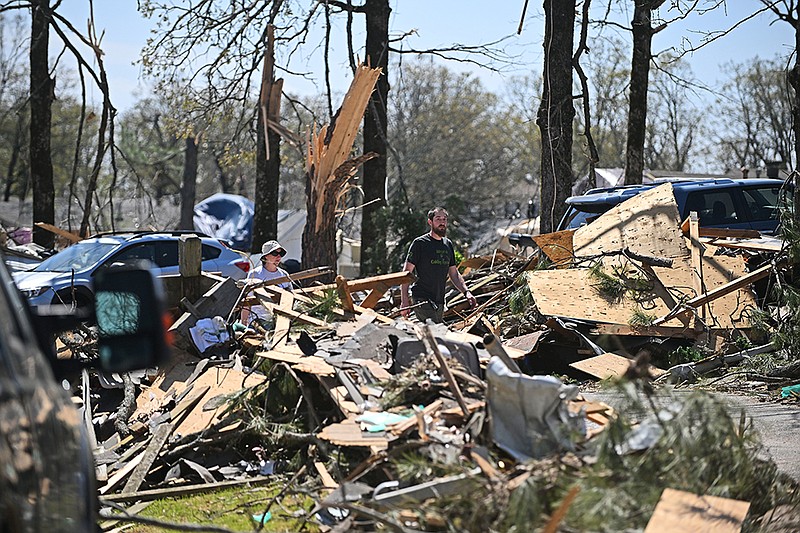 People walk among the piles of debris Sunday, April 2, 2023 in the Indian Hills area of North Little Rock. See more photos at arkansasonline.com/43tornadoes/.(Arkansas Democrat-Gazette/Staci Vandagriff)
