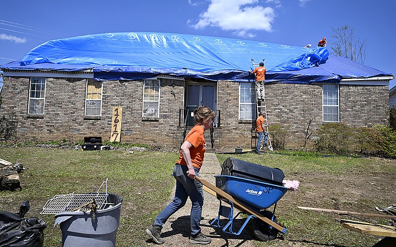 Julia McElrath of Little Rock carries roof tiles to the curb as she and other members of Samaritan’s Purse help clean up Friday on Breckenridge Drive in west Little Rock.
(Arkansas Democrat-Gazette/Stephen Swofford)