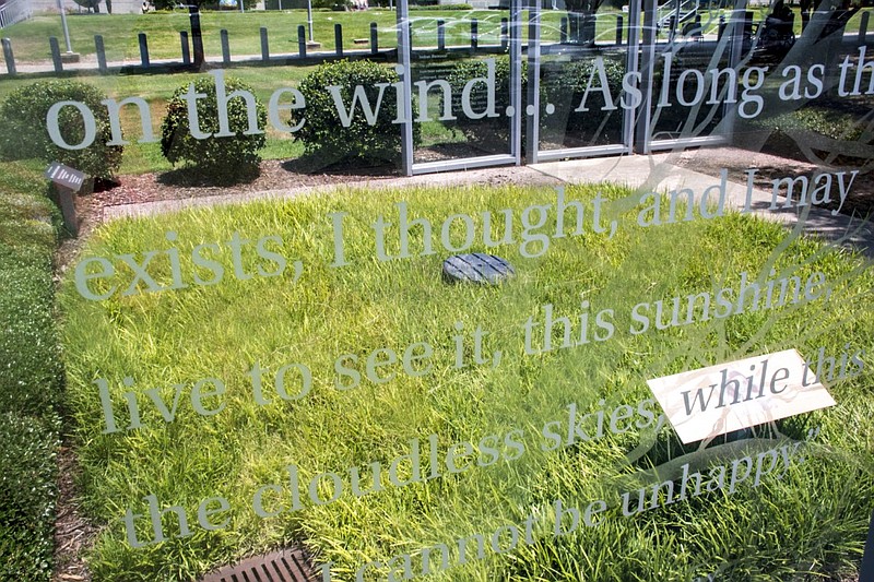 The Anne Frank installation on the grounds of the Clinton Presidential Center in Little Rock is visible through a 10-foot-tall etched glass panel in this July 6, 2022 file photo. The panel previously accompanied the Anne Frank tree, a sapling that was taken from a chestnut tree that once stood outside the house where Anne Frank and her family hid from the Nazis during World War II. The sapling did not survive in Arkansas' climate. (Arkansas Democrat-Gazette/Cary Jenkins)