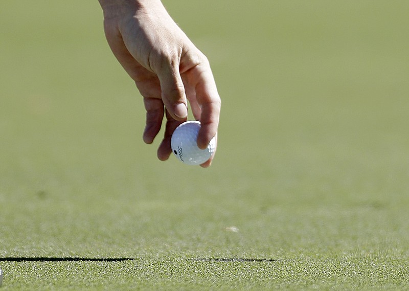 A golfer picks his golf ball out of the cup after putting on the fourth hole in Atlanta in this Sept. 23, 2012 file photo. (AP/David Goldman)