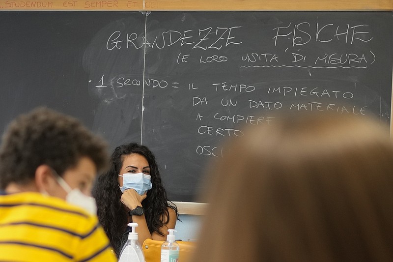 A teacher and students wear face masks during a lesson at a high school in Rome in this Sept. 13, 2021 file photo. The Italian language on the blackboard suggests that the students are being tested on how scientists determine the length of one second. (AP/Andrew Medichini)