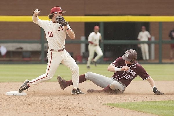 Arkansas second baseman Peyton Stovall (left) throws as Texas A&M's Brett Minnich slides into second base during a game Saturday, April 29, 2023, in Fayetteville.