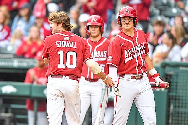 Arkansas second baseman Peyton Stovall (10) celebrates with third baseman Caleb Cali (6) after Stovall scored, Friday, April 28, 2023, during the third inning of the Razorbacks’ 10-4 win over Texas A&M in Fayetteville.
