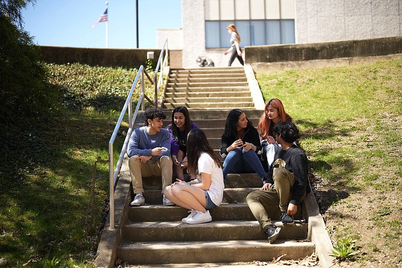 Upper Darby High School students Rayan Hansali, from left, Tanveer Kaur, Elise Olmstead, Fatima Afrani, Joey Ngo and Ata Ollah, talk in the campus courtyard, Wednesday, April 12, 2023, in Drexel Hill, Pa. For some schools, the pandemic allowed experimentation to try new schedules. Large school systems including Denver, Philadelphia and Anchorage, Alaska, have been looking into later start times. (AP Photo/Matt Slocum)