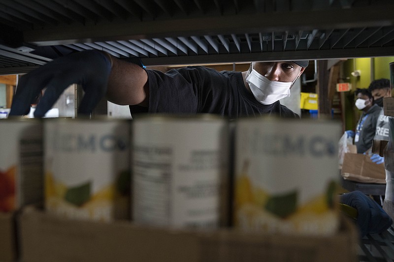 Allen Stewart, 26, a Food and Rescue Coordinator at Bread for the City adds food items to the food pantry, Wednesday, May 10, 2023, in Washington. (AP Photo/Jacquelyn Martin)