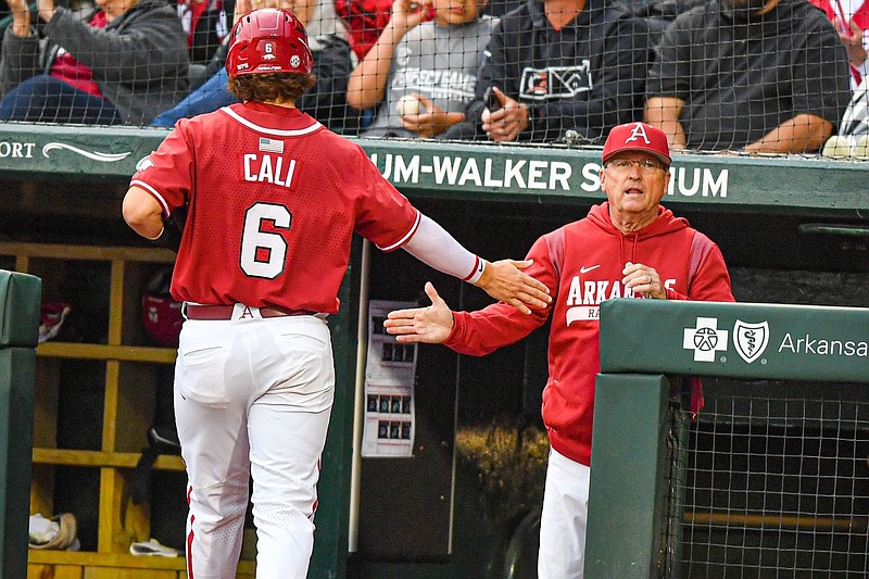 Arkansas head coach Dave Van Horn (center) high-fives third baseman Caleb Cali (6), Friday, April 28, 2023, after Cali scored during the second inning of the Razorbacks’ 10-4 win over the Texas A&M Aggies at Baum-Walker Stadium in Fayetteville.