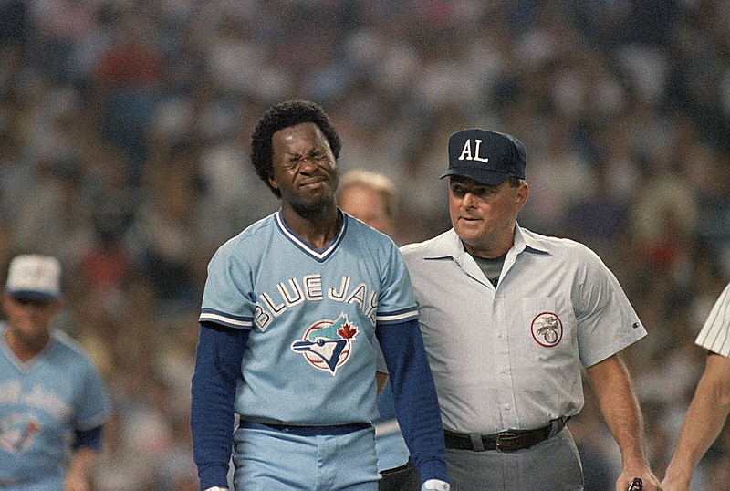 Tony Fernandez of the Toronto Blue Jays, left, grimaces as he tries to clear his head after he was hit on the head by a pitched ball thrown by the New York Yankees rookie Dave Eiland in the second inning, as umpire Don Denkinger looks on, Thursday, Aug. 11, 1988, Yankee Stadium, New York. (AP Photo/Ray Stubblebine)