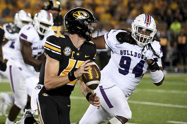 Missouri quarterback Brady Cook, left, scrambles as Louisiana Tech defensive lineman Keivie Rose defends during the second half of an NCAA college football game Thursday, Sept. 1, 2022, in Columbia, Mo. (AP Photo/L.G. Patterson)