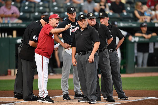 Arkansas coach Dave Van Horn (left) talks with umpires and South Carolina coach Mark Kingston prior to a game Friday, May 12, 2023, in Fayetteville.