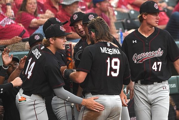 South Carolina catcher Cole Messina (19) is congratulated after scoring a run during a game against Arkansas on Saturday, May 13, 2023, in Fayetteville.