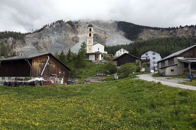 Residential buildings and a church stand in front of the "Brienzer Rutsch" the rockfall danger zone in Brienz-Brinzauls, Switzerland, Friday, May 12, 2023. Authorities in eastern Switzerland have ordered residents of the tiny village of Brienz to evacuate by Friday evening because geology experts say a mass of 2 million cubic meters of Alpine rock looming overhead could break loose and spill down in coming weeks. (AP Photo/Arnd Wiegmann)