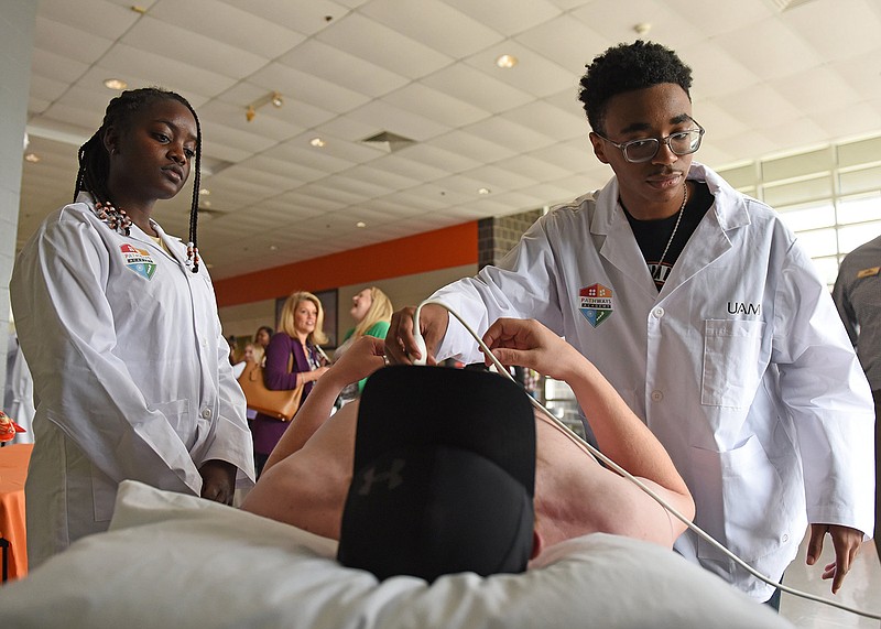 Jerrick Whitted (right), a Hall High School student, demonstrates an ultrasound of arteries and veins in the neck on Stephen Blissett as fellow student Kayla Hampton looks on during the Academies of Central Arkansas business partnership announcement at the school in Little Rock on Wednesday.
(Arkansas Democrat-Gazette/Staci Vandagriff)