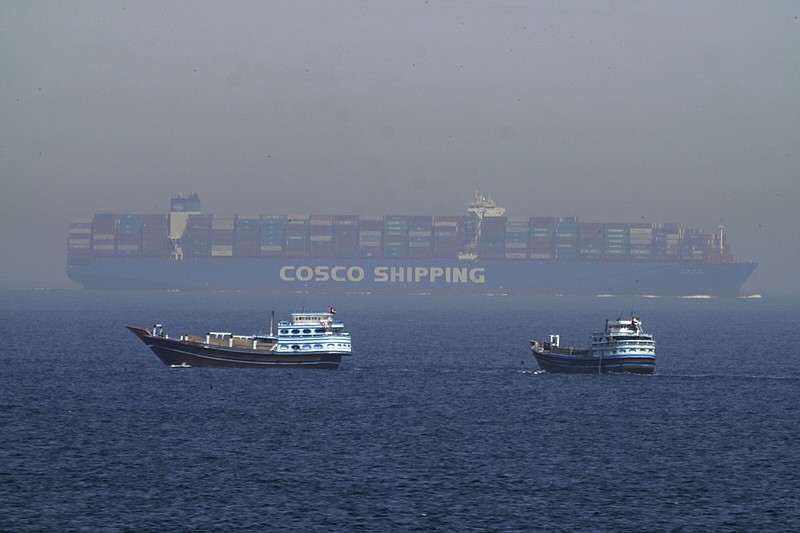 Two traditional dhows sail by a large container ship Friday in the Strait of Hormuz.
(AP/Jon Gambrell)
