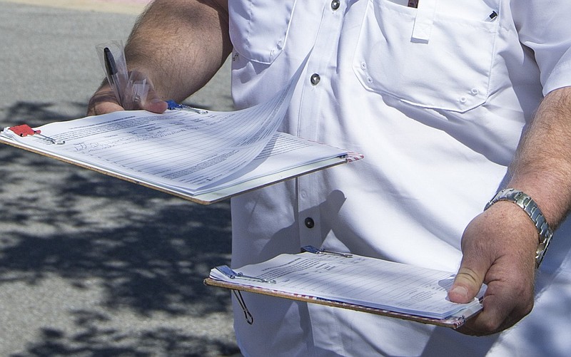 A canvasser takes a signature for a proposed ballot initiative outside the Bentonville Revenue Office in this May 29, 2020 file photo. (NWA Democrat-Gazette/Ben Goff)