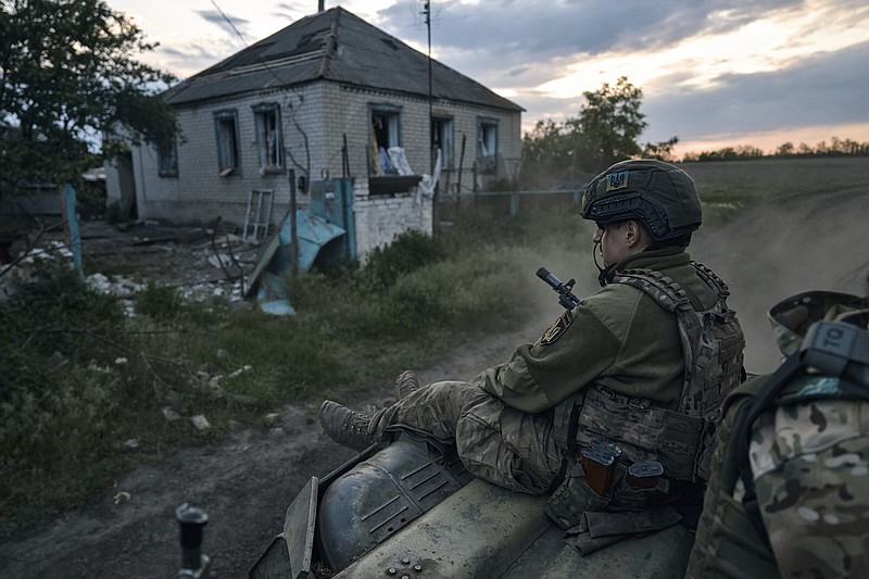 A Ukrainian soldier rides atop an APC on the frontline in the Luhansk region, Ukraine, Sunday, May 21, 2023. (AP Photo/Libkos)