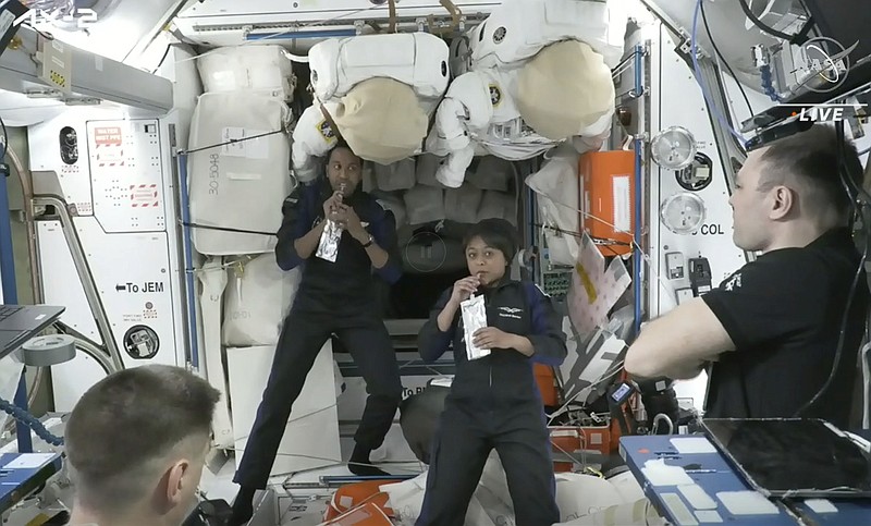 In this image from NASA TV, Ali al-Qarni, second from left, and Rayyanah Barnawi of Saudi Arabia, second right, have a drink alongside two cosmonauts in the International Space Station, Monday, May 22, 2023. The space station rolled out the welcome mat for the two Saudi visitors, including the kingdom's first female astronaut. (NASA TV via AP)