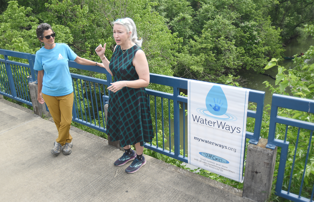 Staff photo by Matt Hamilton / WaterWays executive director Mary Beth Sutton, left, looks on as Maria Price speaks on the Tennessee River Walk about the trash booms on Tuesday, May 23, 2023.