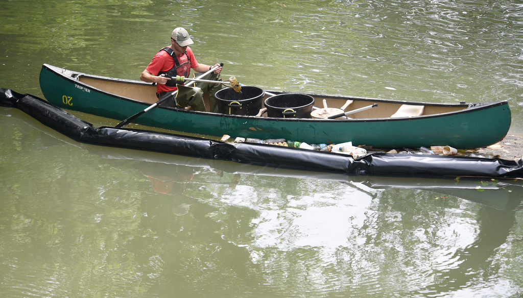 Staff photo by Matt Hamilton / Jack Bates with the Osprey Initiative collects trash on Chattanooga Creek gathered at the trash boom on Tuesday, May 23, 2023.