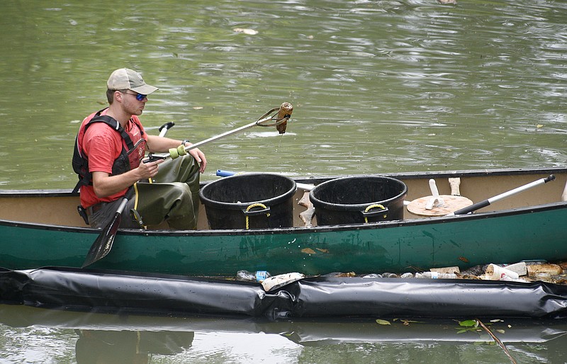 Staff photo by Matt Hamilton / Jack Bates with the Osprey Initiative collects trash on Chattanooga Creek gathered at the trash boom on Tuesday, May 23, 2023.