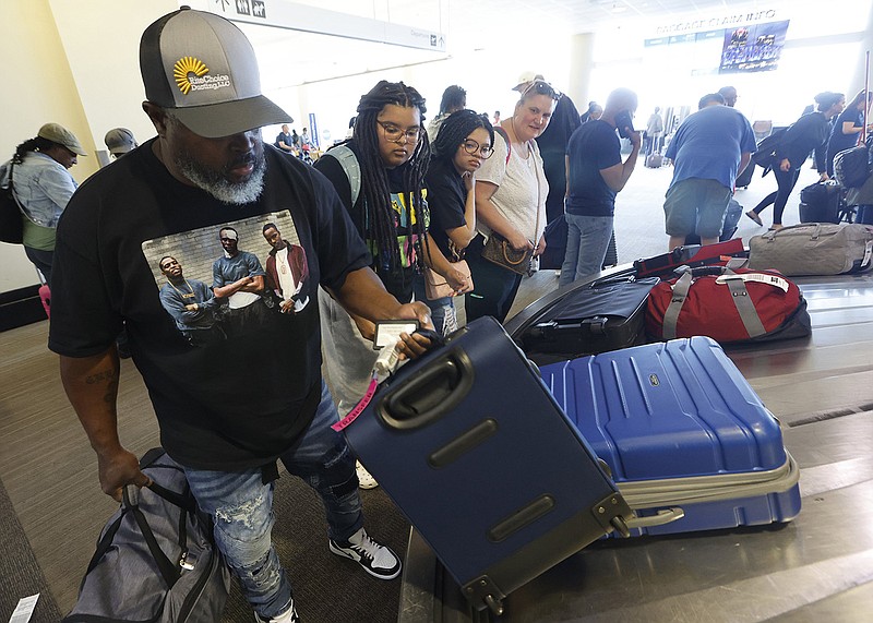 Vince Oliver (from left) looks for his bags with his family, daughters Tianna and Makenna and wife Lisa, in the baggage claim area of Bill and Hillary Clinton National Airport on Thursday in Little Rock.
(Arkansas Democrat-Gazette/Thomas Metthe)