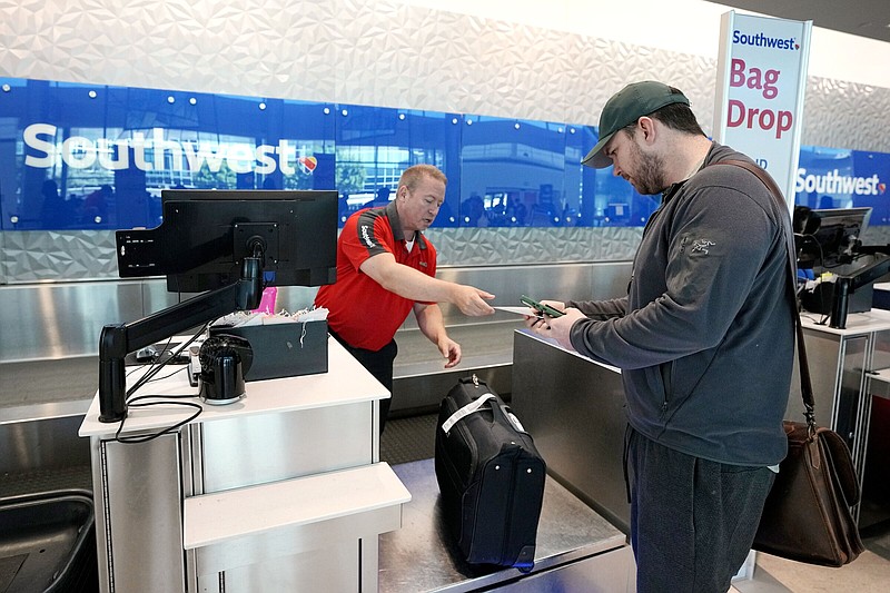 A man checks his bags with a customer service representative Friday at the Southwest ticketing gate at Love Field airport in Dallas.
(AP/Tony Gutierrez)