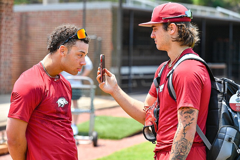 Pitcher Brady Tygart (right) and outfielder Tavian Josenberger joke around on a video call during the Arkansas Razorbacks’ practice Friday at Hoover High School in Hoover, Ala. Tygart will start on the mound for the Razorbacks today against Texas A&M in the SEC Baseball Tournament semifinals.
(NWA Democrat-Gazette/Hank Layton)