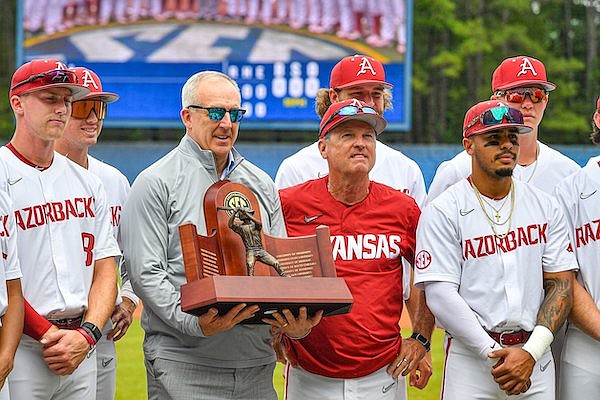 Greg Sankey (center, left), commissioner of the Southeastern Conference, presents Arkansas head coach Dave Van Horn (center, right) and his team a trophy for being co-champions of the conference, Wednesday, May 24, 2023, before the first inning of the Razorbacks’ 6-5 extra-innings win over the Texas A&M Aggies at the 2023 SEC Baseball Tournament at the Hoover Metropolitan Complex in Hoover, Ala.