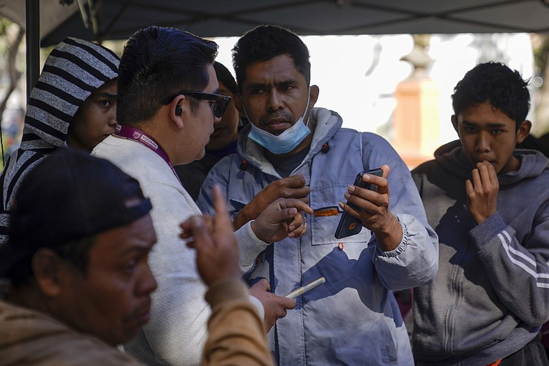 FILE- Migrants get help with the CBPOne app from a Tijuana, Mexico city worker Tuesday, Jan. 24, 2023, in Tijuana, Mexico. (Associated Press file photo)