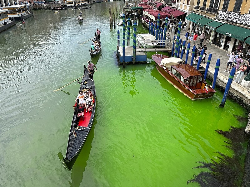 A bright patch of green is seen in the Grand Canal along an embankment lined with restaurants, in Venice, Italy, Sunday, May 28, 2023. (AP/Luigi Costantini)