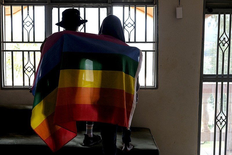 FILE - A gay Ugandan couple cover themselves with a pride flag as they pose for a photograph in Uganda on March 25, 2023. (AP, File)