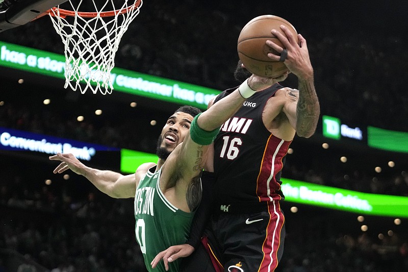 Boston Celtics forward Jayson Tatum, left, and Miami Heat forward Caleb Martin reach for a rebound during the first half in Game 7 of the NBA basketball Eastern Conference finals Monday, May 29, 2023, in Boston. (AP Photo/Charles Krupa )