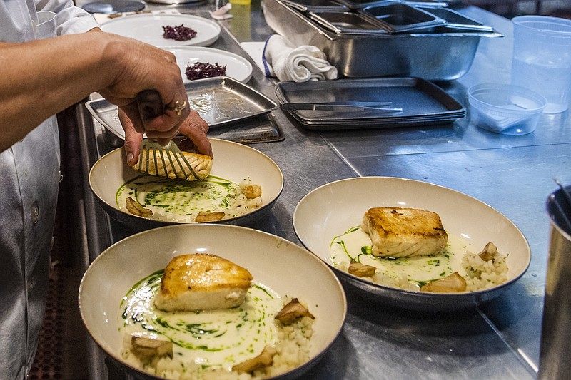 FILE - A worker arranges food onto plates in the kitchen of a restaurant in New York on Dec. 14, 2021. Food workers who showed up while sick or contagious were linked to about 40% of restaurant food poisoning outbreaks with a known cause between 2017 and 2019, federal health officials said Tuesday, May 30, 2023. (AP Photo/Brittainy Newman, File)