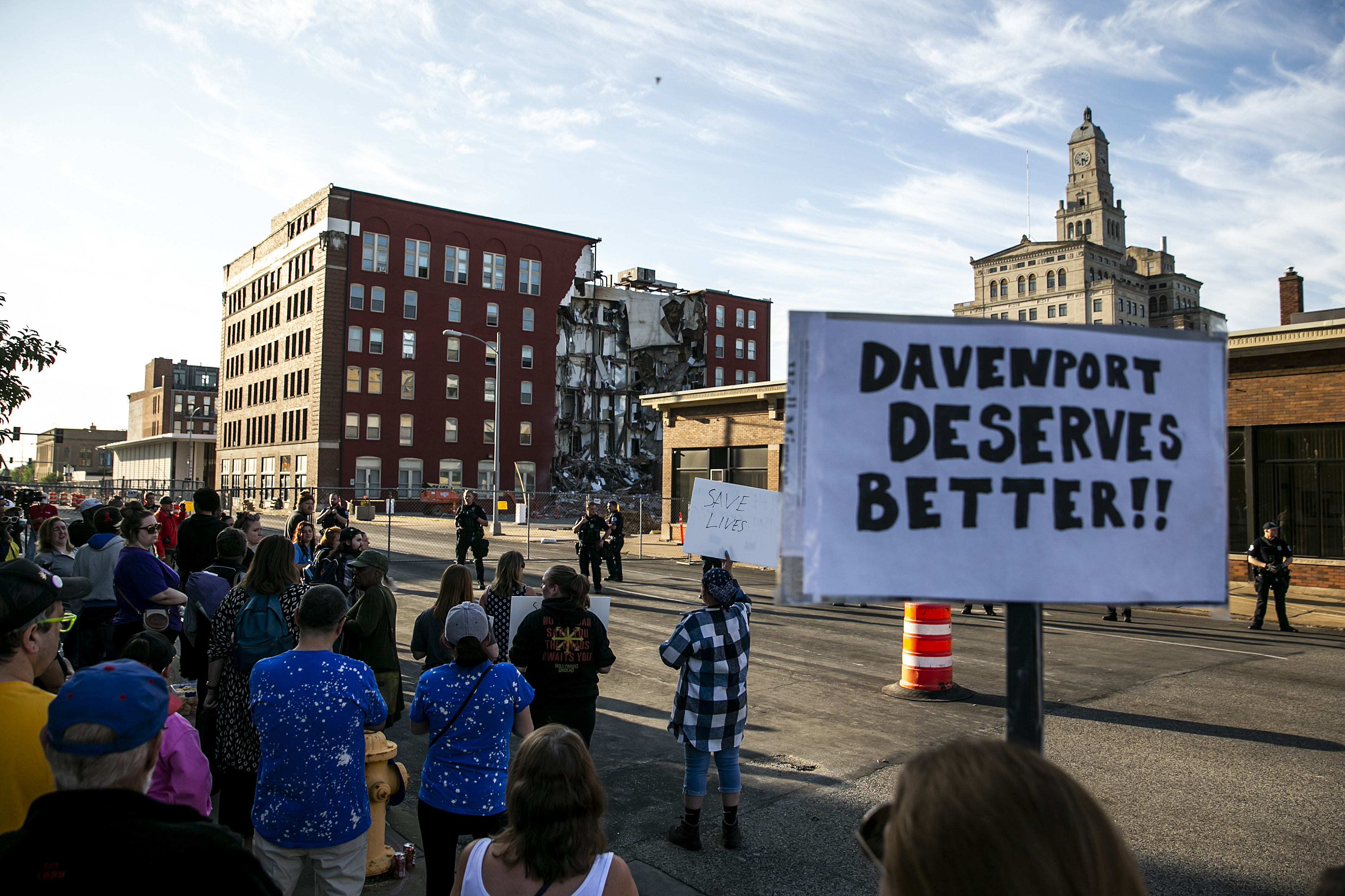 Davenport police officers form a line opposite protesters that are advocating for search efforts to continue, Tuesday, May 30, 2023, near the site of an apartment building that partially collapsed in Davenport, Iowa. A woman was rescued on Monday after calling her family and waving for help, according to multiple news reports. The building partially collapsed on Sunday. (Joseph Cress/Iowa City Press-Citizen via AP)