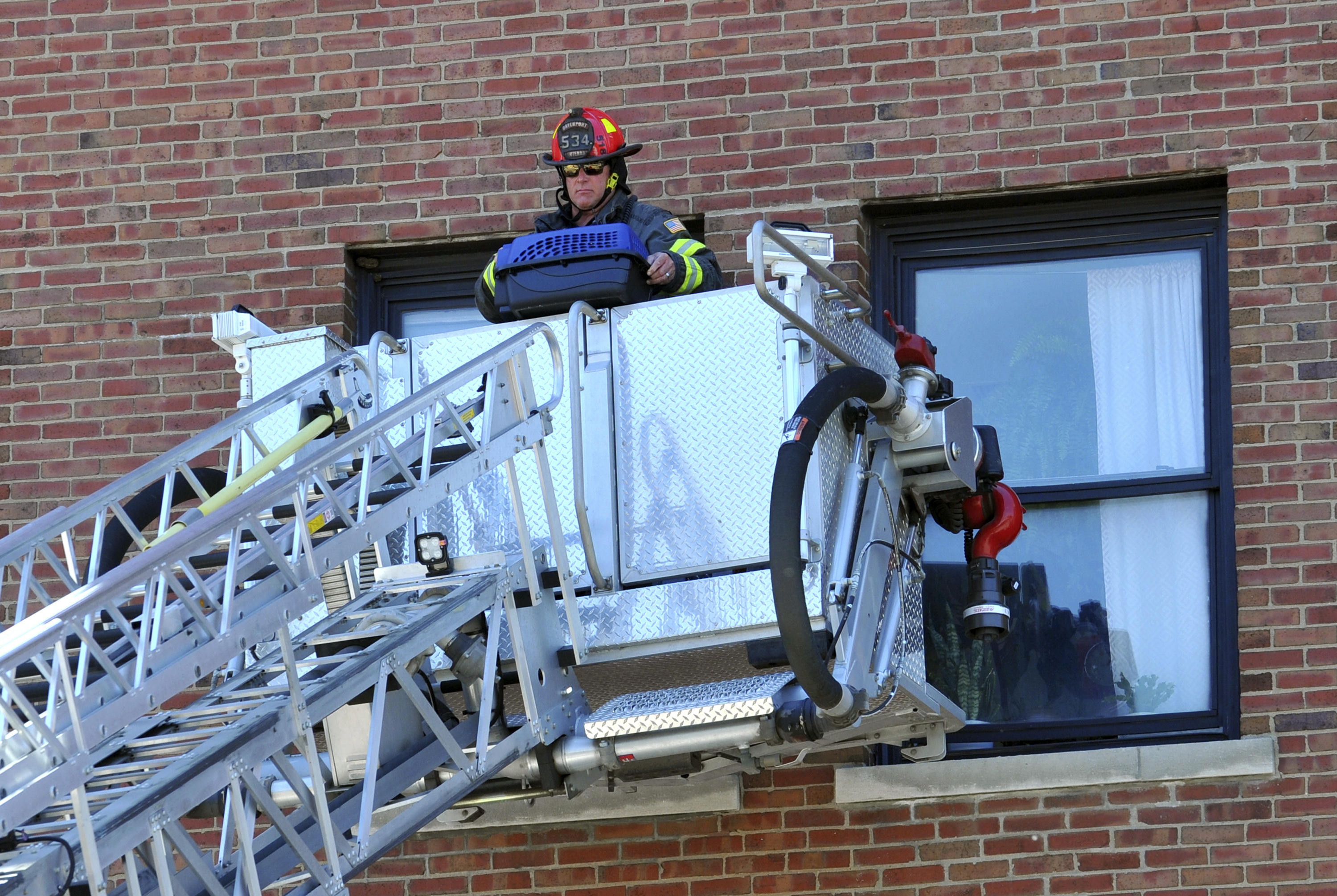 A Davenport firefighter brings down a pet in a pet carrier as search and rescue personnel work the part of The Davenport apartment looking for pets and people inside the partially collapsed building, Tuesday, May 30, 2023, in Davenport, Iowa. Five residents of a six-story apartment building that partially collapsed in eastern Iowa remained unaccounted for Tuesday, and authorities feared at least two of them might be stuck inside rubble that was too dangerous to search. (Gary Krambeck/Quad City Times via AP)