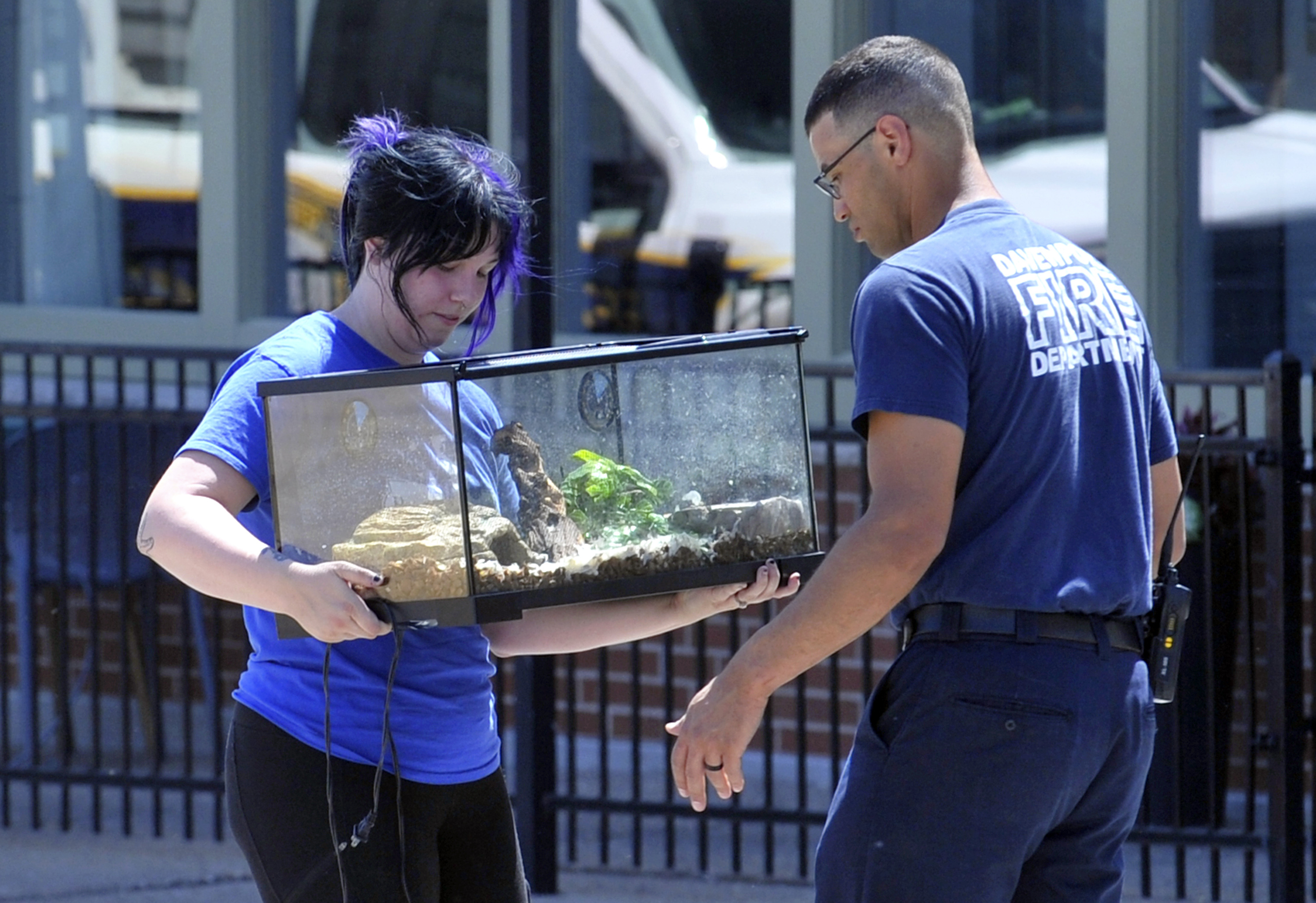 A Davenport firefighter hands over a terrarium to Scott County Humane personnel after it was removed from the partially collapsed apartment building, The Davenport, Tuesday, May 30, 2023, in Davenport, Iowa. Five residents of a six-story apartment building that partially collapsed in eastern Iowa remained unaccounted for Tuesday, and authorities feared at least two of them might be stuck inside rubble that was too dangerous to search. (Gary Krambeck/Quad City Times via AP)