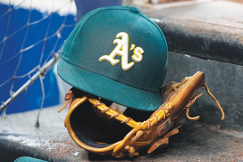 An Athletics hat sits on a glove on the dugout steps before Saturday’s game against the Marlins in Miami. (Associated Press)