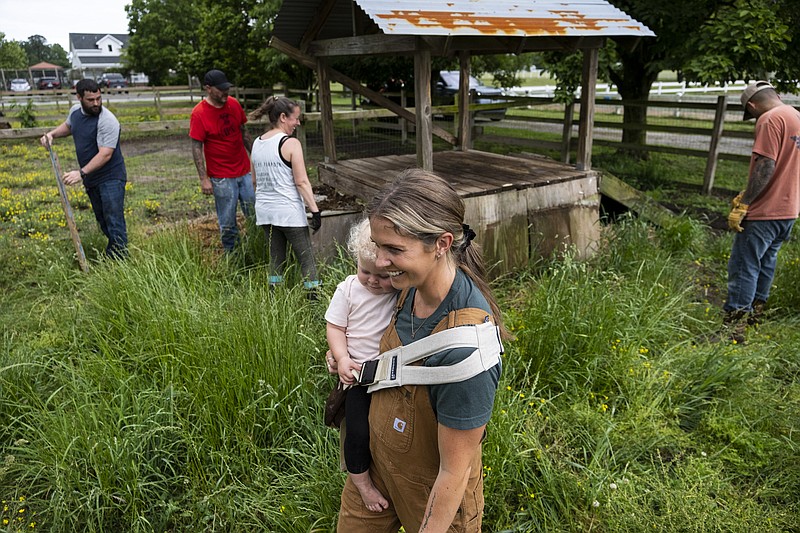 Kayla Arestivo, a therapist with Trails of Purpose, watches as volunteers help move bales of hay on May 20, 2023, in Chesapeake, Va., ahead of the opening of their new location in Virginia Beach, Va. Trails of Purpose provides free mental health services to members of the military. (Billy Schuerman/The Virginian-Pilot via AP)